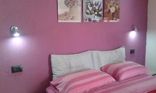 a bedroom with a pink wall with two pillows on a bed at Alma Bed & Breakfast in Sennariolo