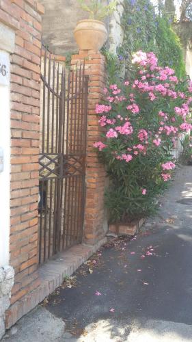 a gate with pink flowers next to a brick building at Sciala' in Taormina