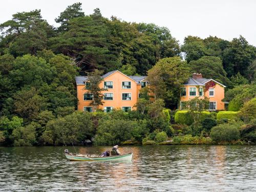 a man in a boat on the water in front of houses at Carrig Country House & Restaurant in Killorglin