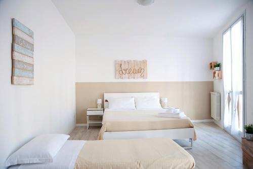 a white bedroom with two beds and a window at Le Mura apartment in Peschiera del Garda