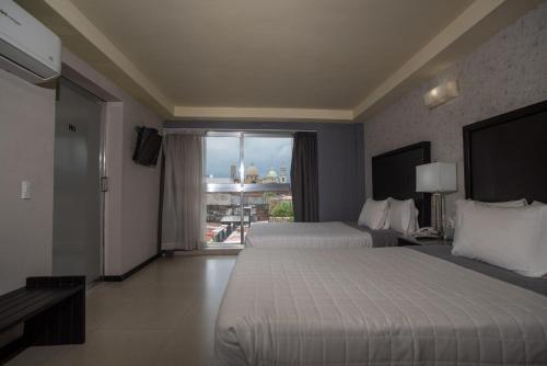 Habitación de hotel con 2 camas y ventana grande. en Hotel Ha en Orizaba