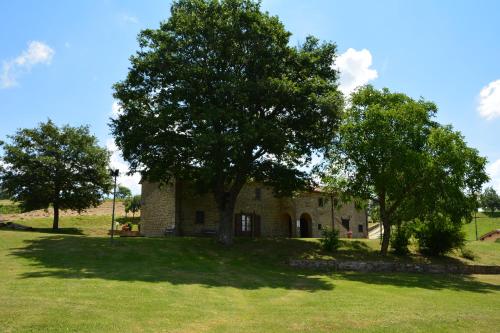 an old stone house with trees in a field at Agriturismo Le Case in Pietralunga