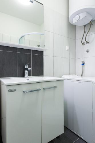 a white bathroom with a sink and a mirror at Apartments Kalelarga in Zadar