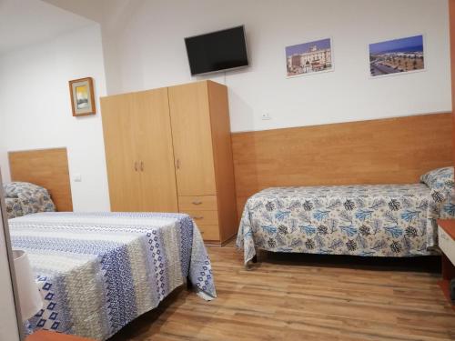 a room with two beds and a tv on the wall at B&B Altamarea in Marina di Schiavonea