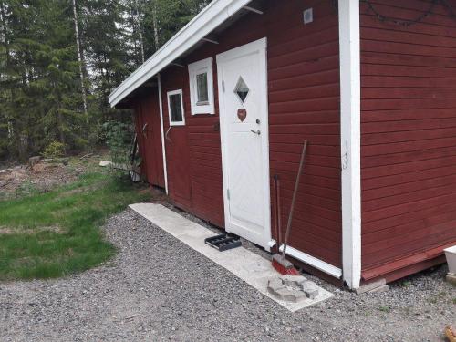 a red house with a white door on the side of it at Hyttingsfabodstugor in Borlänge