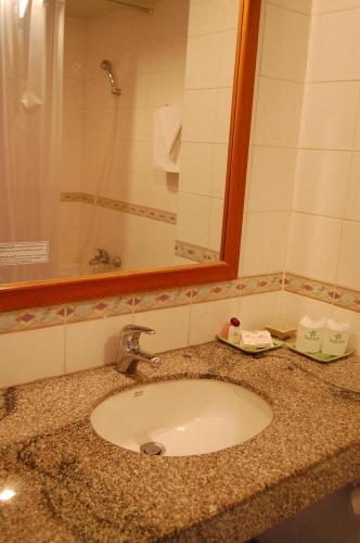 a bathroom counter with a sink and a mirror at Royal Lanna Hotel in Chiang Mai