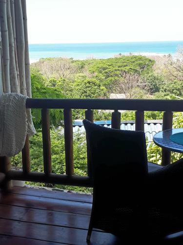 a balcony with a chair and a table and the ocean at Horizon Hotel & Yoga Center in Santa Teresa Beach