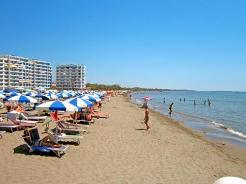 a beach with a bunch of chairs and umbrellas at Domus Hotel & Apartments in Shëngjin