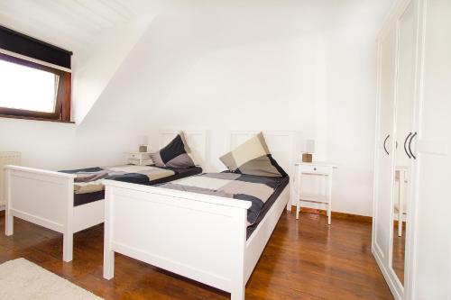 a white bedroom with a bed and a window at Ferienwohnungen BECKENDORF Schiller in Losheim