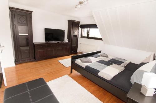 um quarto com uma cama grande e uma televisão de ecrã plano em Ferienwohnungen BECKENDORF Schiller em Losheim