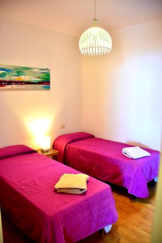 two beds in a room with pink sheets at Taormina Sunny Apartment - Taormina Holidays in Taormina