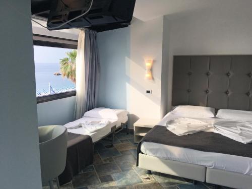 a hotel room with two beds and a large window at BB Oasis in Scilla