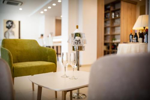 two wine glasses on a table next to a green chair at International Beach Hotel in Caorle