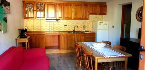 a kitchen with wooden cabinets and a table with a red couch at Appartamento Porto Frailis in Tortolì
