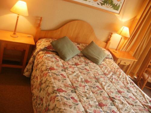 uma cama num quarto de hotel com duas mesas e duas lâmpadas em La Peninsula Rehue em Pucón