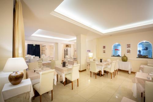 a dining room with white tables and white chairs at International Beach Hotel in Caorle