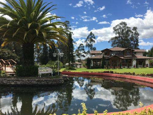 a palm tree and a house with a pond at Casa d'Campo Tababela Hotel Boutique in Tababela