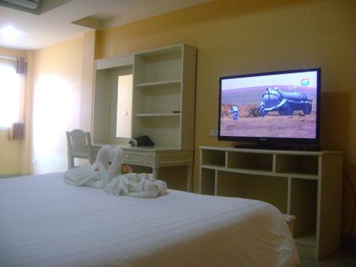 a bedroom with a bed and a flat screen tv at Ploy Puu Residence in Chiang Rai