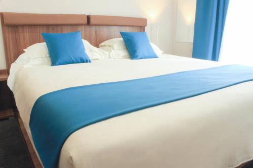 a large bed with blue pillows on top of it at Rooms Villa Oasiss in Pula