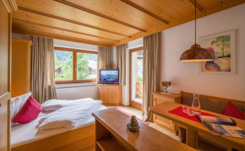 a bedroom with a bed and a table and a tv at Landhaus Gasser in Mayrhofen