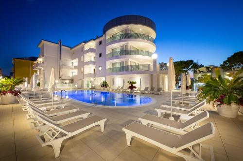 - un bâtiment avec une piscine et des chaises longues devant dans l'établissement International Beach Hotel, à Caorle