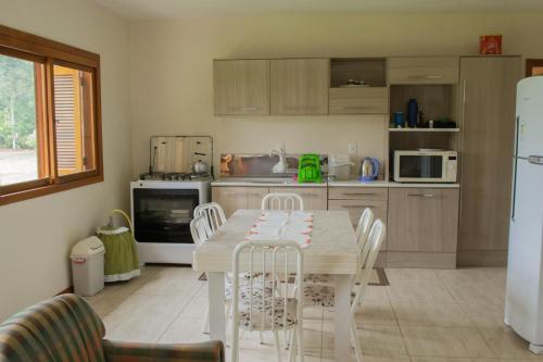 a kitchen with a table and chairs and a refrigerator at Chale Recanto do Belvedere in Gramado