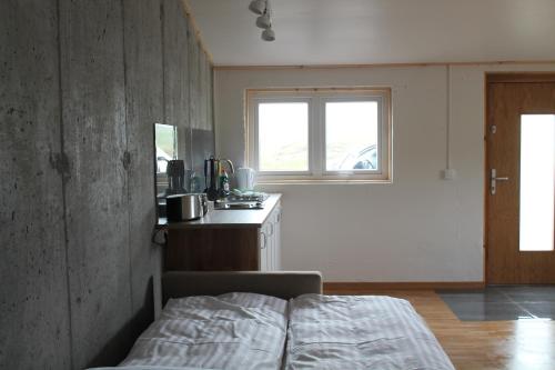 a bedroom with a bed and a kitchen with a window at Lækjarhus Farm Holidays in Borgarhöfn
