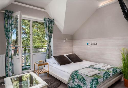 a small bedroom with a bed and a balcony at Orbisa Pokoje i Apartamenty in Łeba
