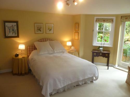 a bedroom with a large white bed with two windows at Laurel House in Cheltenham