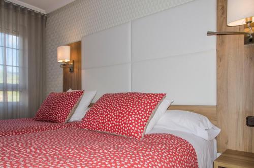 a bedroom with a bed with red and white pillows at Hotel Presa in Riaño