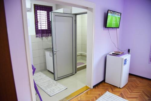 a bathroom with a walk in shower next to a refrigerator at PRENOĆIŠTE PILOT in Niš