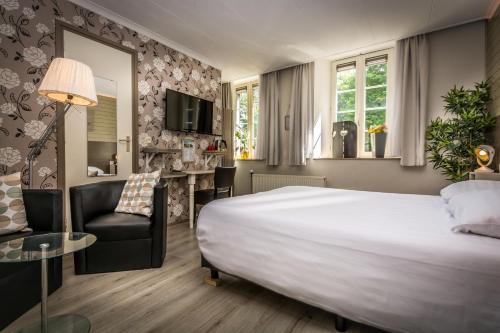 Cette chambre comprend un grand lit et une chaise. dans l'établissement Carré Hotel Zuid-Limburg, à Hulsberg