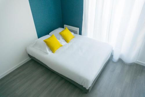 łóżko z 2 żółtymi poduszkami w pokoju w obiekcie BtoBed - Paris Nord Villepinte w Villepinte