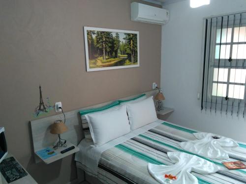 a bedroom with a bed and a picture on the wall at Hospedagem Da Laranjeira Gramado in Gramado