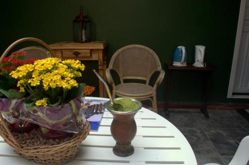 a table with flowers and a vase on it at Hospedagem Da Laranjeira Gramado in Gramado