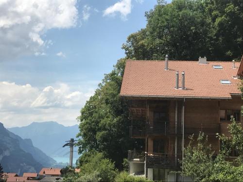 an old house with a red roof and mountains in the background at Alp n' rose in Hasliberg