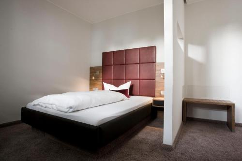 a bedroom with a large bed with a red headboard at Hotel Gräfrather Hof in Solingen