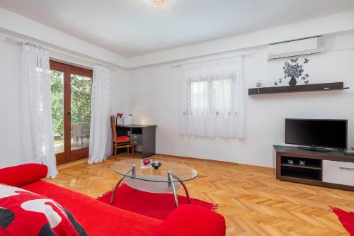 a living room with a red couch and a table at Guest House Ravnić in Poreč
