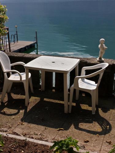 a white table and two chairs next to the water at Le palme Antonella in Cima