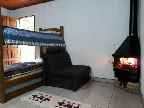 a bedroom with a bed and a chair and a fireplace at Casa Estilo Kitnet in Campos do Jordão