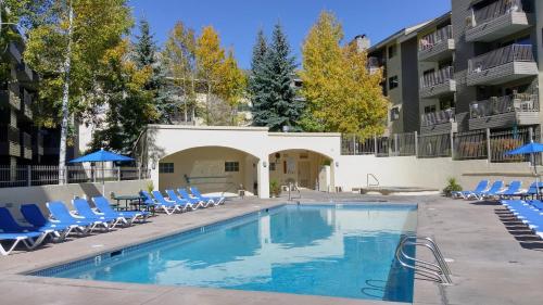 a swimming pool with lounge chairs and a building at Beaver Creek West Condos in Avon