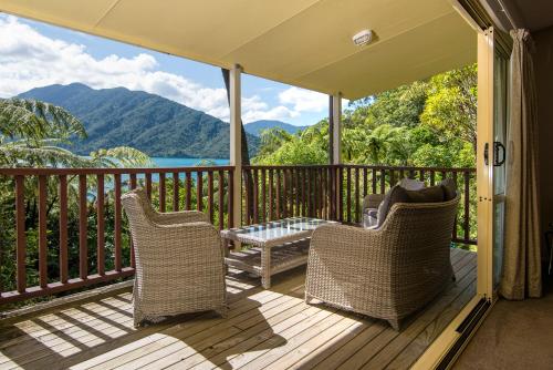 a porch with two chairs and a table on a deck at Punga Cove Resort in Endeavour Inlet