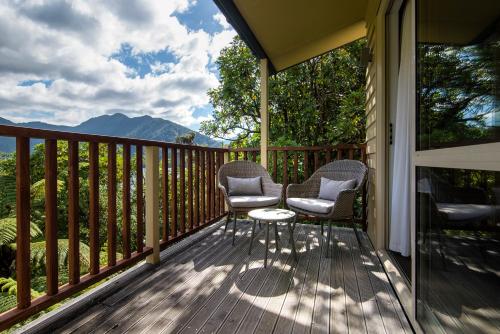 two chairs and a table on a deck with a view at Punga Cove Resort in Endeavour Inlet