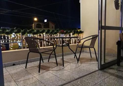 2 sillas y una mesa en el balcón por la noche en Hotel Calmelia en Piura
