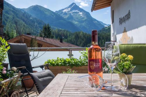 a bottle of wine sitting on a wooden table with a glass at Pension Alpengruss in Gerlos