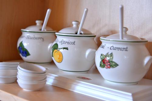 three white pots on a shelf with bowls and utensils at Pension Alpengruss in Gerlos