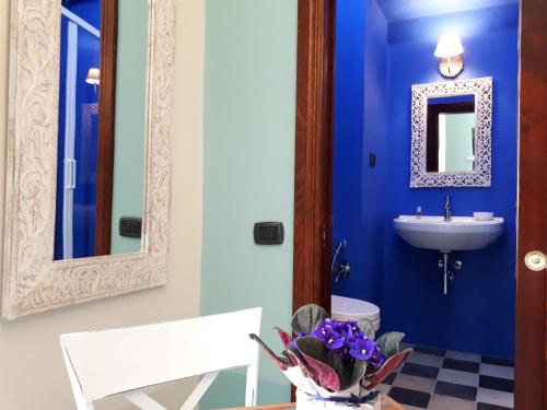 Baño azul con lavabo y espejo en Sofia Family Suites, en Carloforte