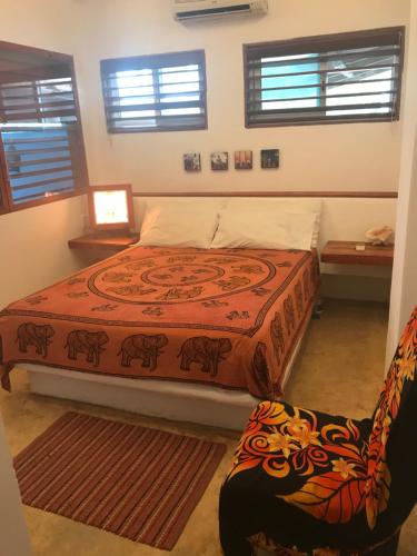 a bedroom with a bed and a chair and windows at Casa de las Olas Surf & Beach Club in Acapulco