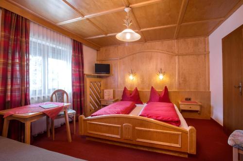 a bedroom with a large wooden bed with red pillows at Pension Alpengruss in Gerlos