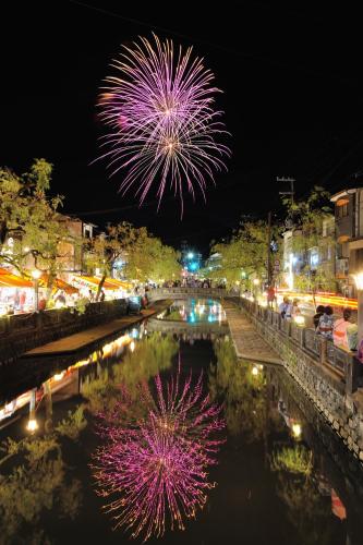 a firework display over a river at night at Koyado Enn in Toyooka